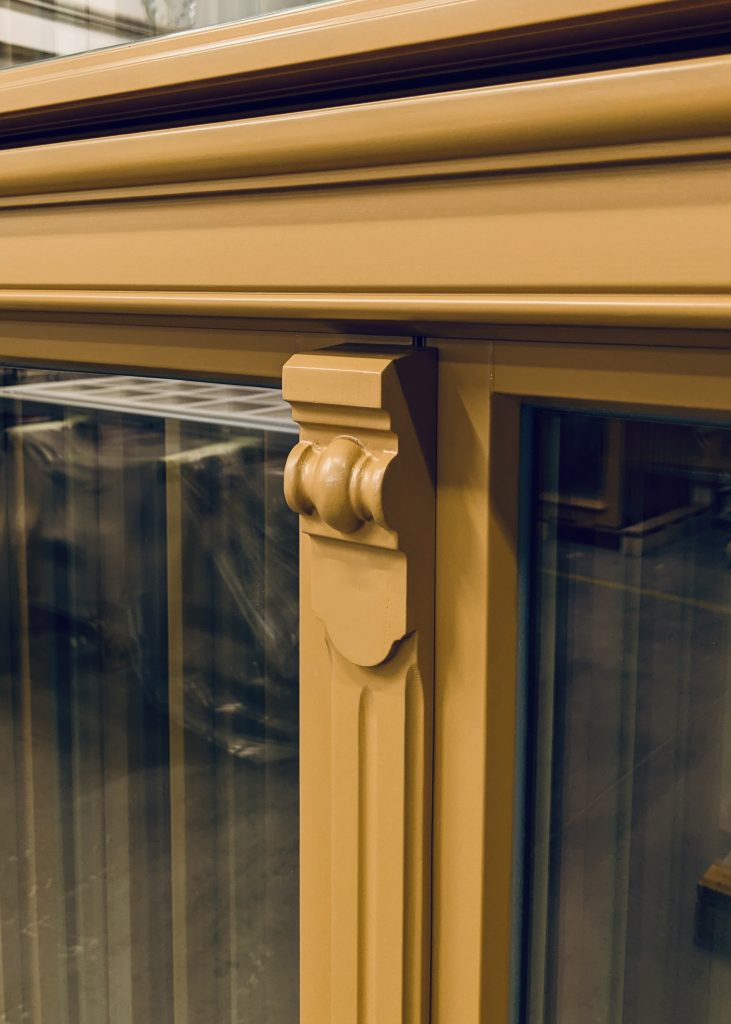 Nagemaakt detail: console met bol op de gecanneleerde stijl, oker gelakt